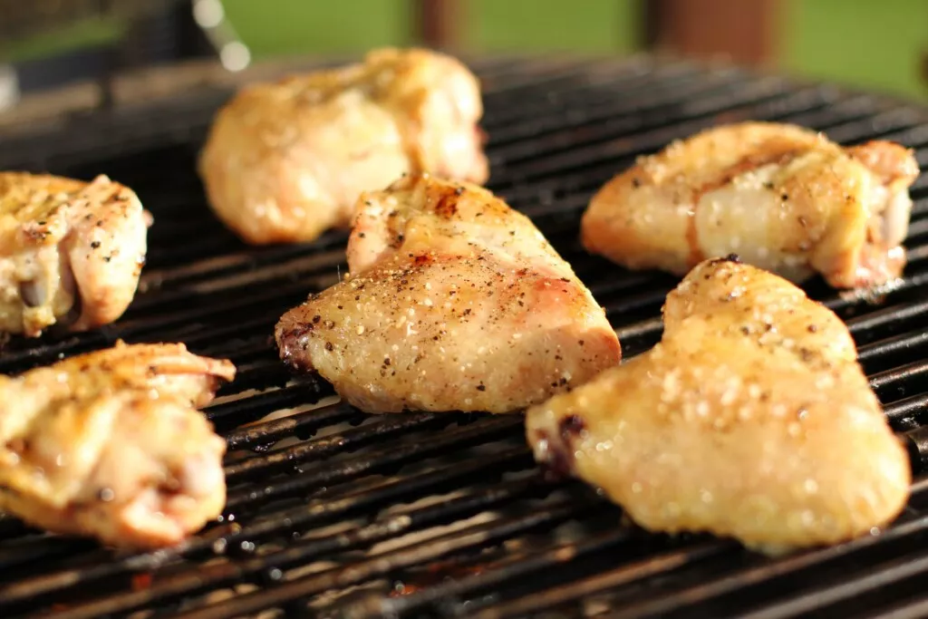 Chicken wings are shown on a grill, cooked and coated in seasoning.