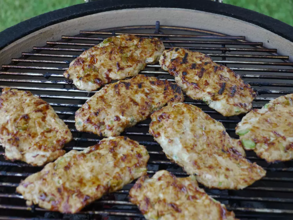 Marinated pork chops are shown on a kamado cooking grid.